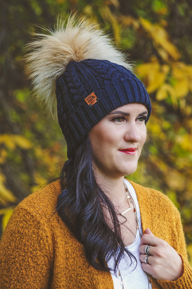 Woman wearing a navy colored unisex style Braided Knit Acrylic Toque that a real fur pom can be added to.