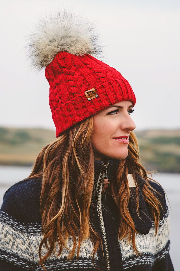 Woman wearing a navy colored unisex style Braided Knit Acrylic Toque that a real fur pom can be added to.